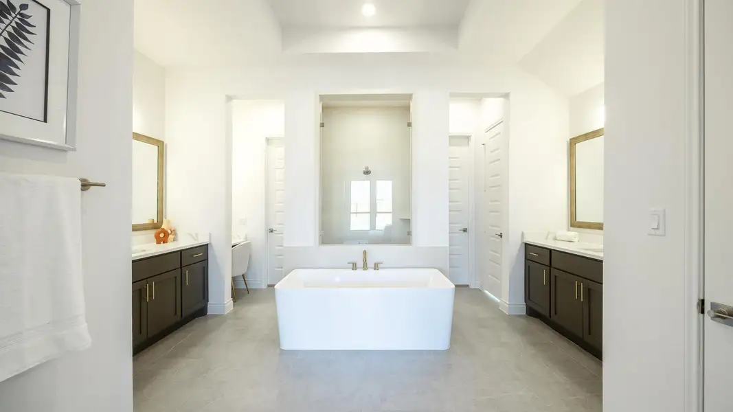 Full bathroom featuring a soaking tub, baseboards, and two vanities