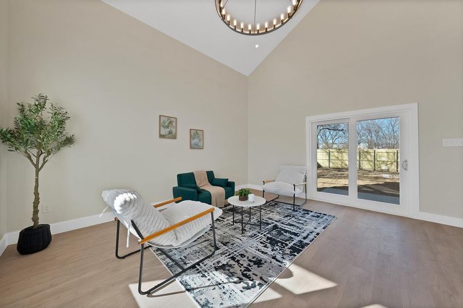 Living area featuring high vaulted ceiling, light wood-type flooring, and a chandelier