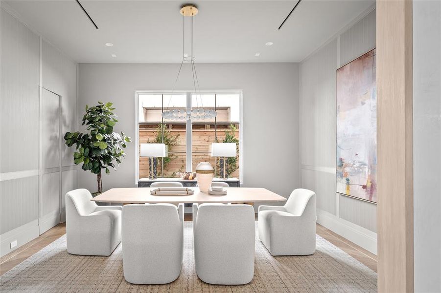 This refined dining room exudes sophistication, anchored by a striking Sean Lavin Orbet 30 chandelier that casts a warm, inviting glow. Two fixed glass windows provide natural light and serene views, enhancing the airy ambiance. The space is grounded by stunning herringbone white oak hardwood floors with a brass inlay border, adding a touch of luxury to this thoughtfully designed setting.