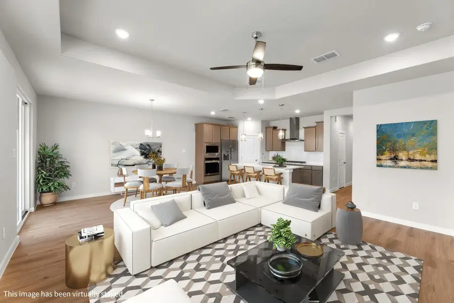 An open-concept living area seamlessly connects the kitchen and dining spaces, featuring warm wood flooring and recessed lighting. An open-concept living area seamlessly connects the kitchen and dining spaces, featuring warm wood flooring and recessed lighting.