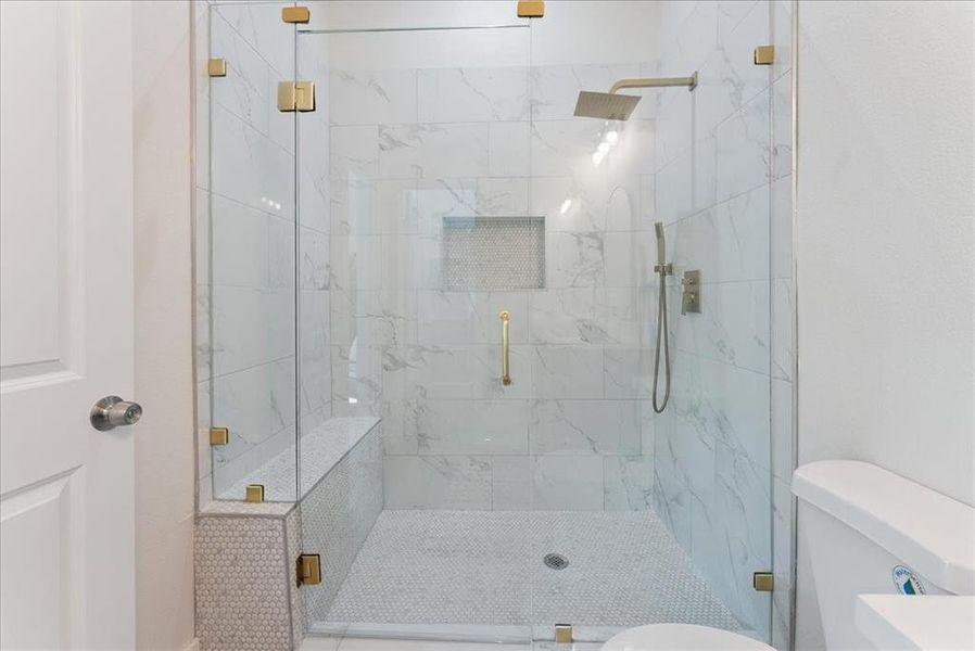 Bathroom with a marble finish shower and toilet
