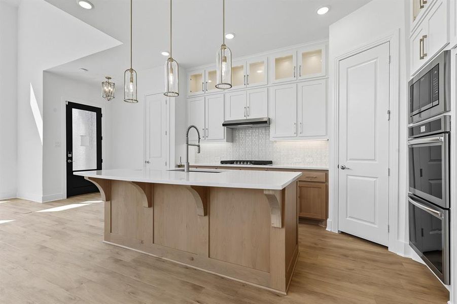 Kitchen featuring glass insert cabinets, stainless steel appliances, a breakfast bar, backsplash, and recessed lighting Kitchen featuring glass insert cabinets, stainless steel appliances, a breakfast bar, backsplash, and recessed lighting