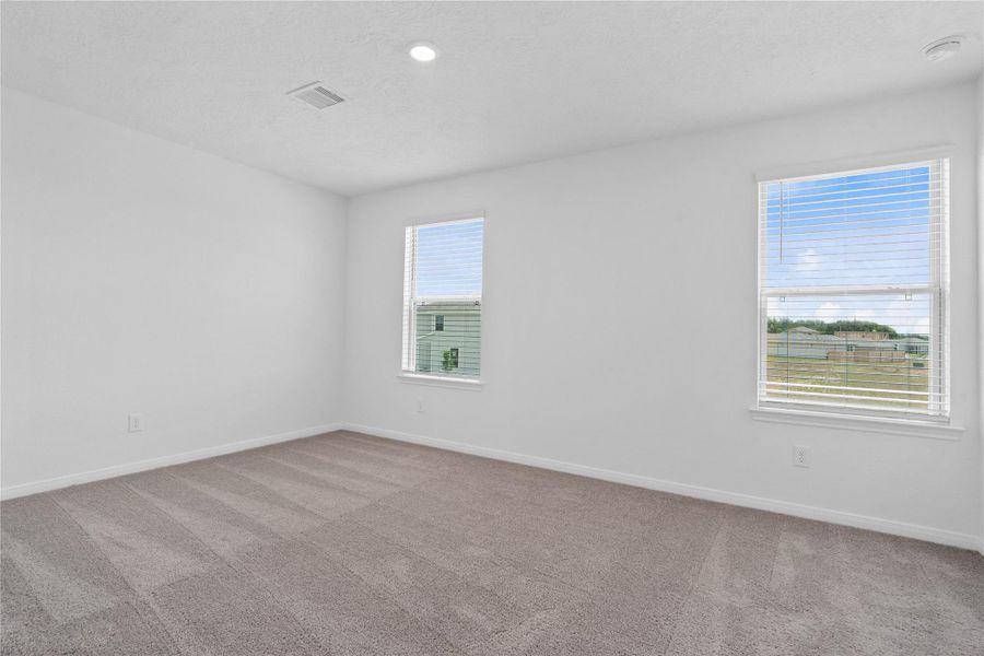 Well appointed secondary bedroom that features plush carpeting, neutral paint tones, recessed lighting, large windows with fitted blinds, and a generously sized closet. Well appointed secondary bedroom that features plush carpeting, neutral paint tones, recessed lighting, large windows with fitted blinds, and a generously sized closet.