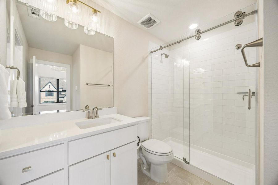 THIS SECONDARY BATH FEATURES A GLASS-ENCLOSED SHOWER, WHITE SUBWAY TILE, QUARTZ VANITY, AND CLEAN NEUTRAL FINISHES. THIS SECONDARY BATH FEATURES A GLASS-ENCLOSED SHOWER, WHITE SUBWAY TILE, QUARTZ VANITY, AND CLEAN NEUTRAL FINISHES.