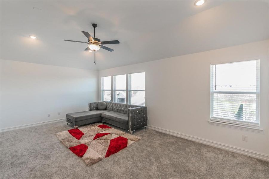 Unfurnished living room featuring carpet flooring, vaulted ceiling, and ceiling fan