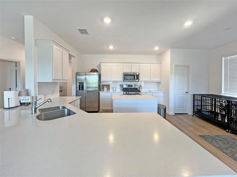 Kitchen featuring backsplash, white cabinetry, appliances with stainless steel finishes, a peninsula, and recessed lighting