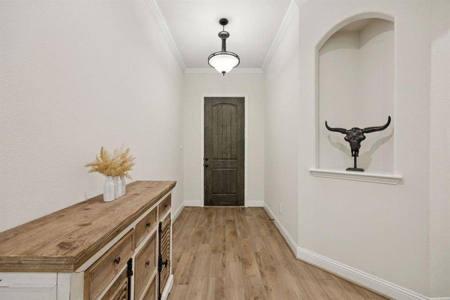 Entryway featuring an art niche, arched walkways, crown molding, luxury vinyl plank flooring, and recessed lighting.