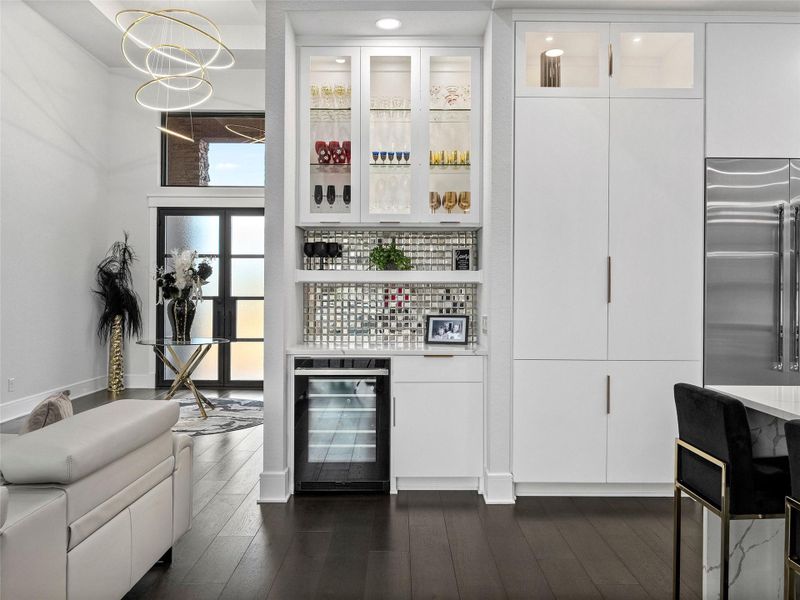 Bar featuring glass fronted cabinets, beverage cooler, white cabinets, built in refrigerator, and dark wood finished floors