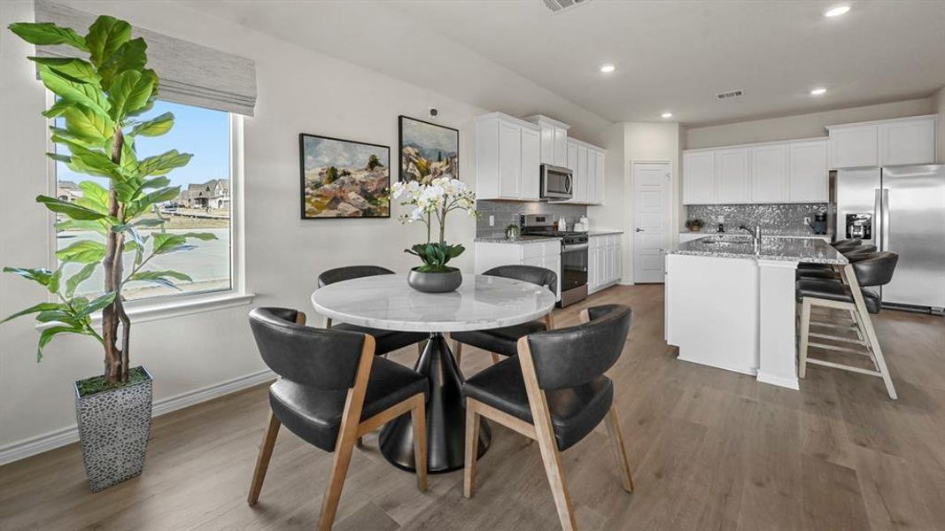 Kitchen featuring decorative backsplash, stainless steel appliances, white cabinetry, a breakfast bar area, and dark wood-type flooring
