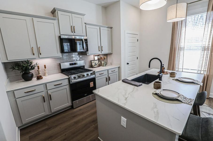 Kitchen featuring a central island with an undermount sink, light-toned countertops, and pendant lighting