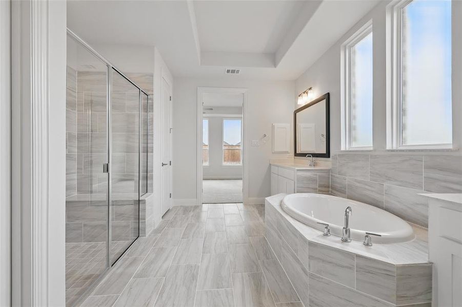 Full bath featuring a stall shower, vanity, a garden tub, baseboards, and visible vents