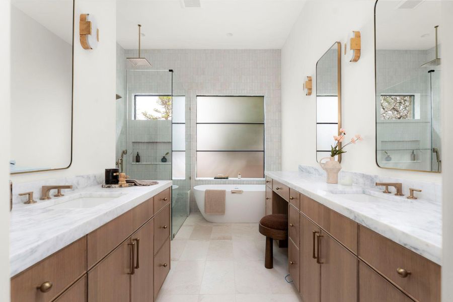 Bathroom with two vanities, a freestanding tub, and a tile shower