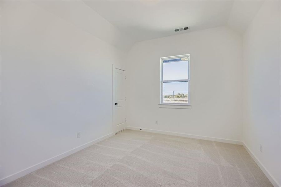 Empty room with light colored carpet and vaulted ceiling