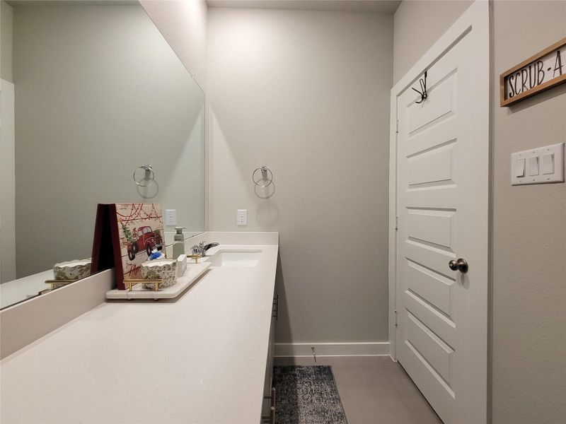 This secondary bathroom features a clean, modern design with a spacious countertop, large mirror, and minimalist decor. The neutral color palette and ample lighting create a bright, inviting space.