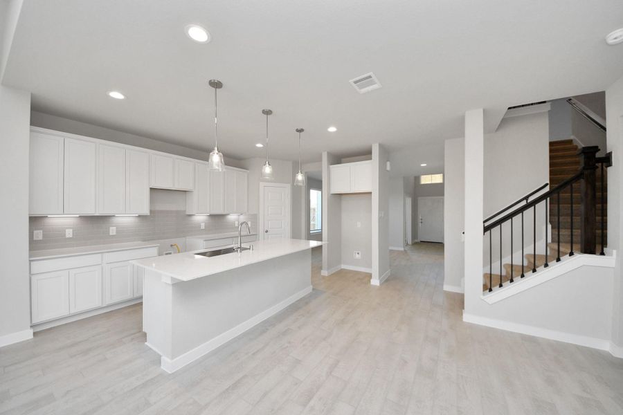 The kitchen is a culinary haven, featuring granite countertops, a tile backsplash, stainless steel appliances, 42” upper cabinets, and undercabinet lighting. Sample photo of completed home with similar floor plan. Actual colors and selections may vary. The kitchen is a culinary haven, featuring granite countertops, a tile backsplash, stainless steel appliances, 42” upper cabinets, and undercabinet lighting. Sample photo of completed home with similar floor plan. Actual colors and selections may vary.