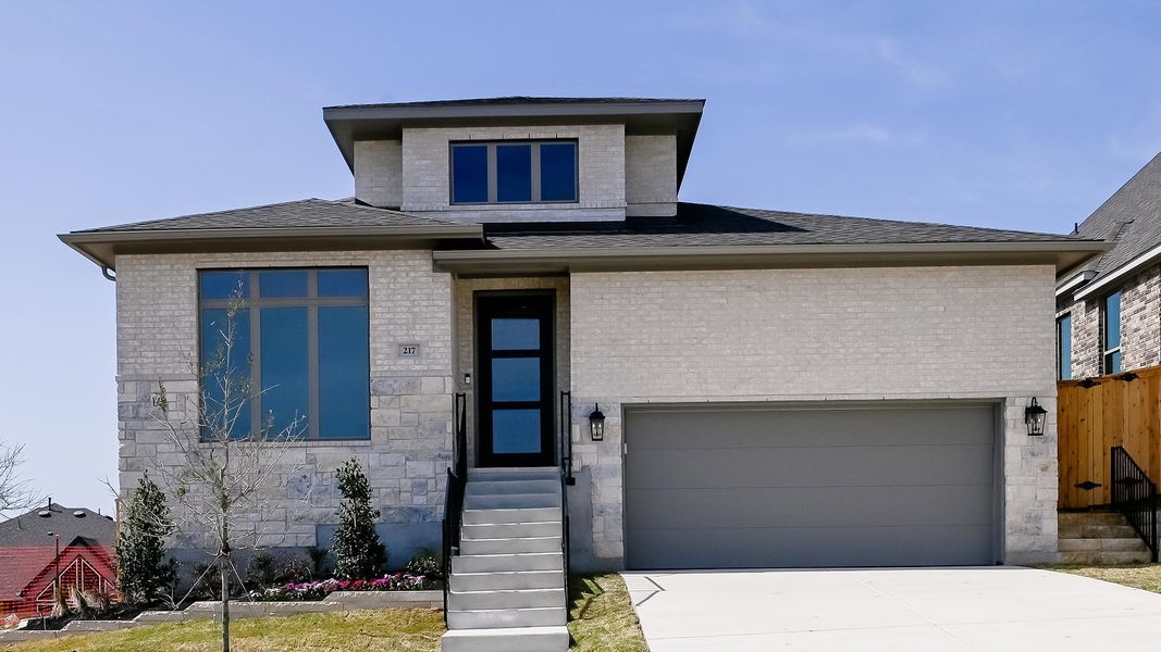 Prairie-style home with brick siding, concrete driveway, and fence Prairie-style home with brick siding, concrete driveway, and fence