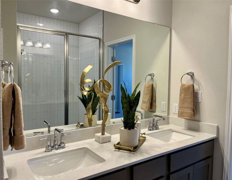 Full bathroom with double vanity, a textured wall, and a shower stall