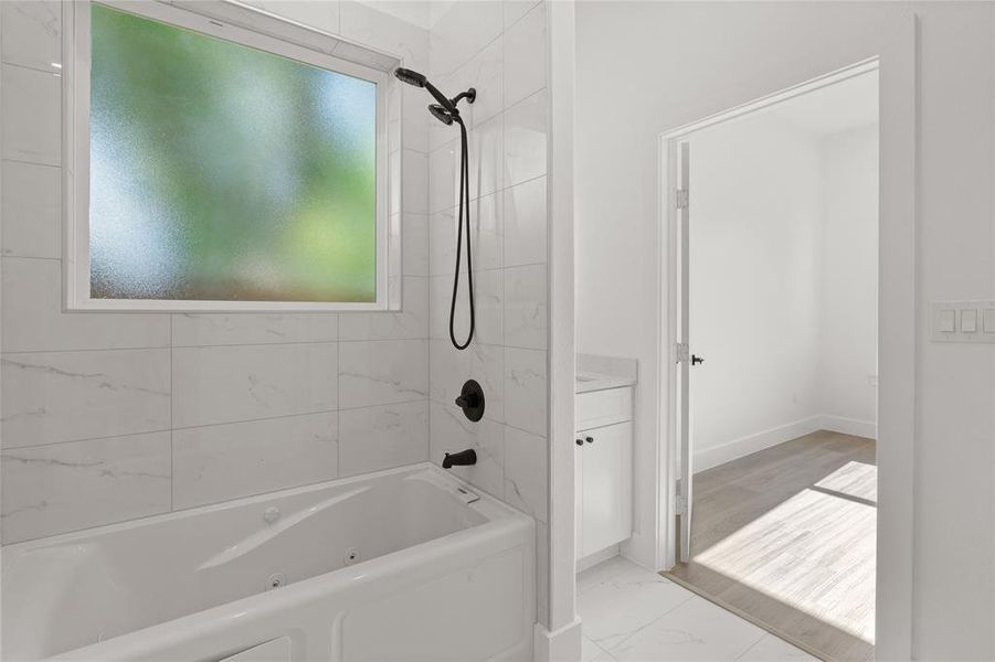 Bathroom featuring marble finish floors, a combined bath / shower with jetted tub, and vanity