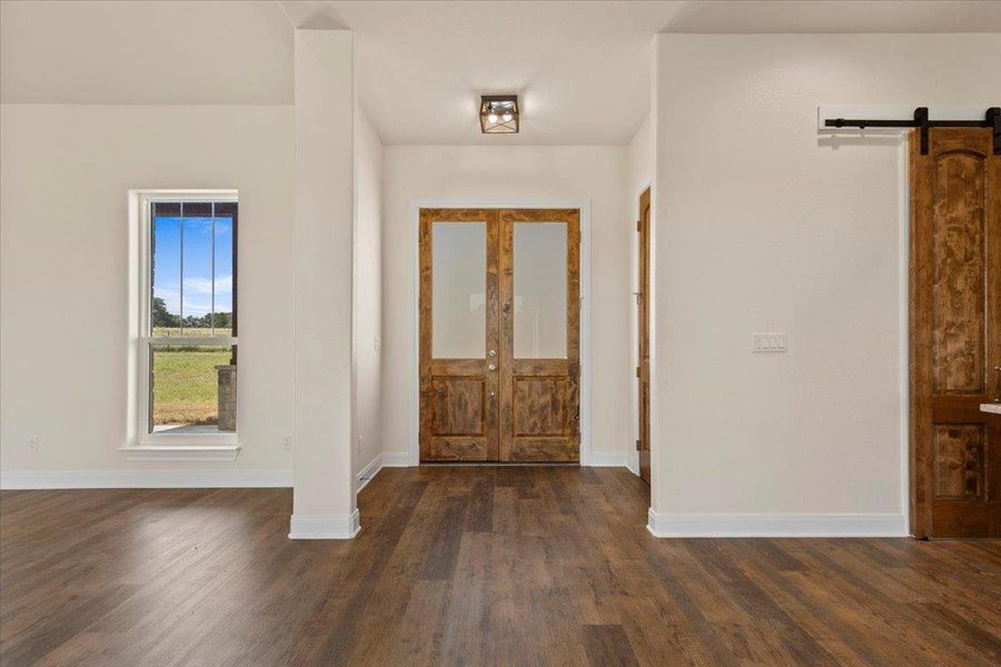 Foyer featuring a barn door and dark wood-style flooring
