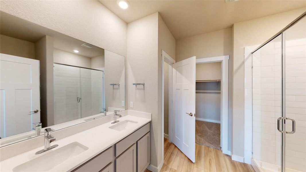 Full bathroom featuring a stall shower, light wood-style flooring, double vanity, a spacious closet, and recessed lighting