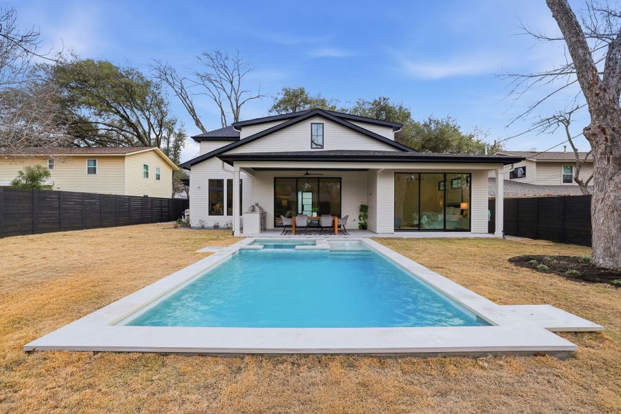 Rear view of house with a patio area, a fenced backyard, and a pool with connected hot tub