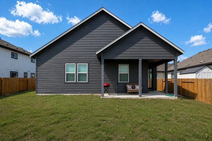 Backyard featuring a covered patio, dark gray horizontal siding, white trim windows, and a wood privacy fence Backyard featuring a covered patio, dark gray horizontal siding, white trim windows, and a wood privacy fence