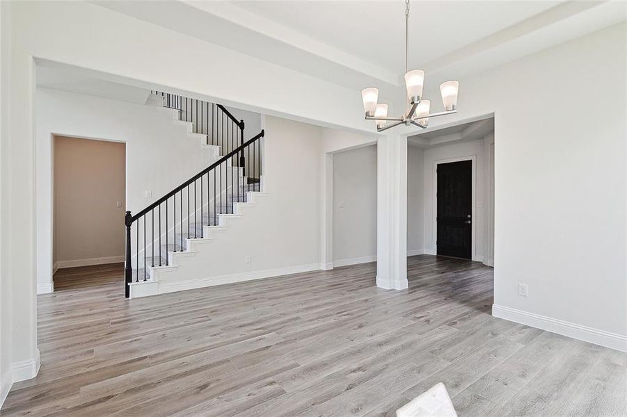 Empty room with light wood-type flooring and a chandelier