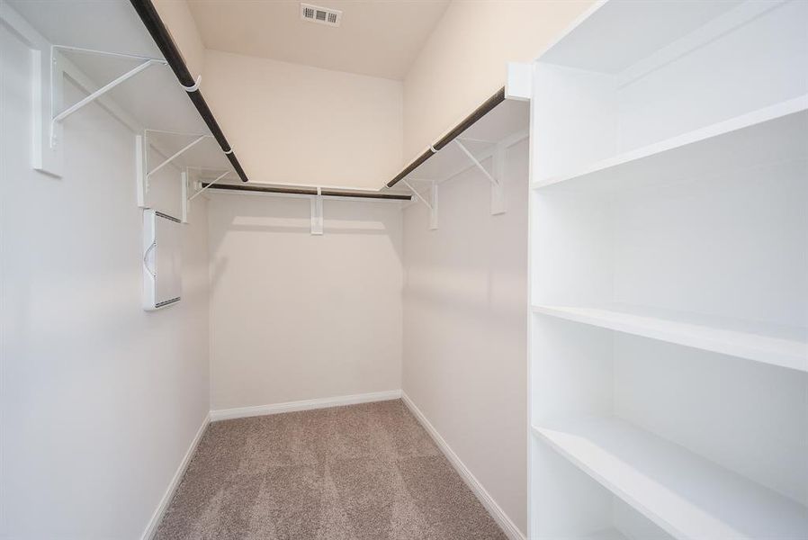 A spacious closet for the primary bedroom with built-in shelving. A spacious closet for the primary bedroom with built-in shelving.