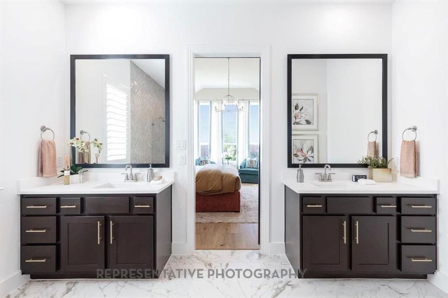 Ensuite bathroom with light marble finish flooring, two vanities, and healthy amount of natural light