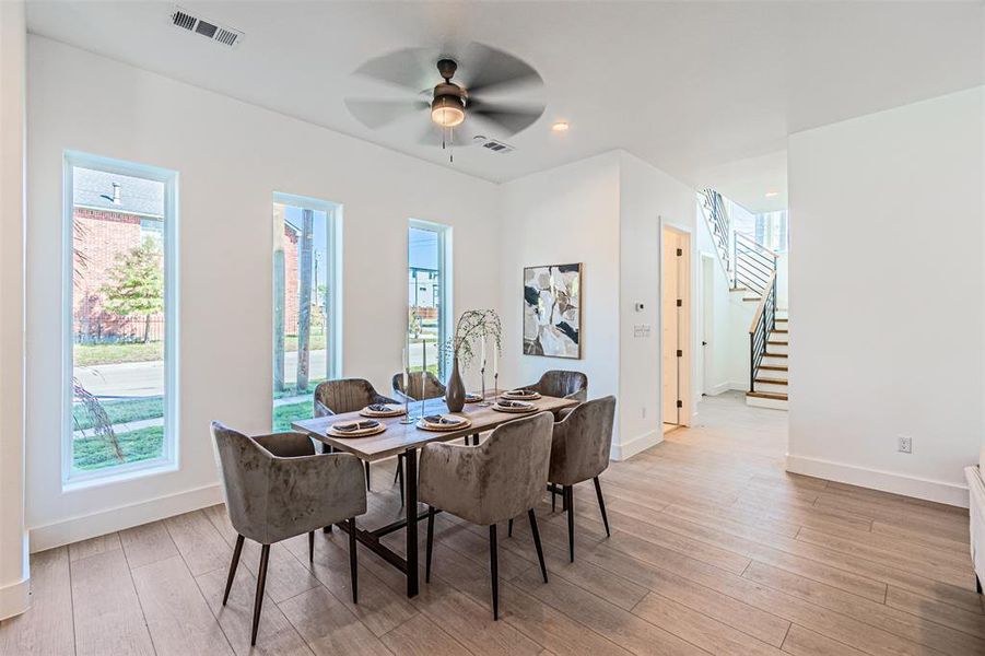 Dining room featuring stairway, light wood finished floors, and ceiling fan Dining room featuring stairway, light wood finished floors, and ceiling fan