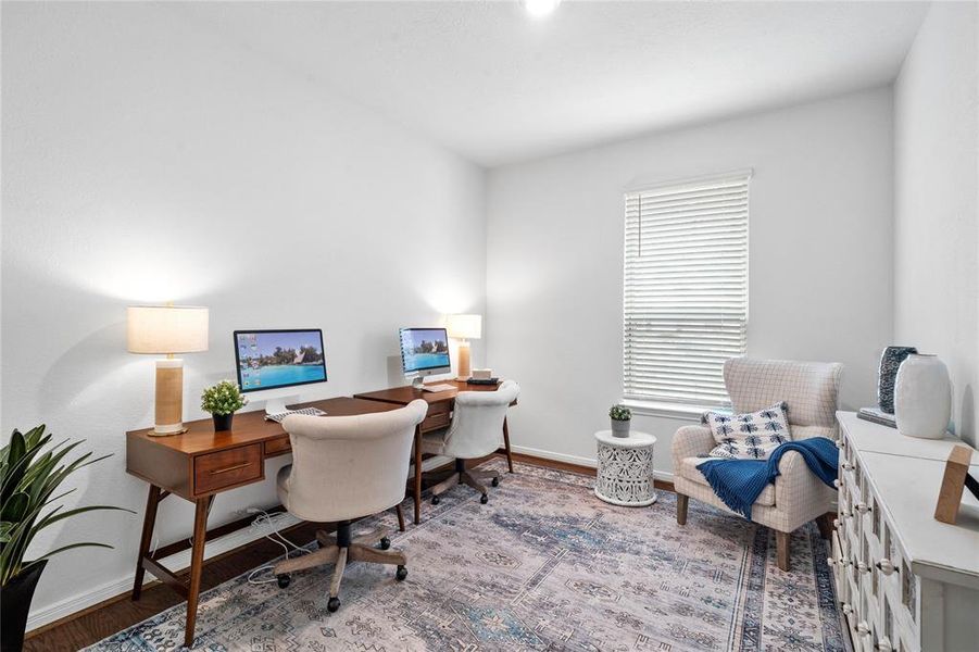 This handsome home office features plush carpet, high ceilings, large windows with privacy blinds and neutral paint.