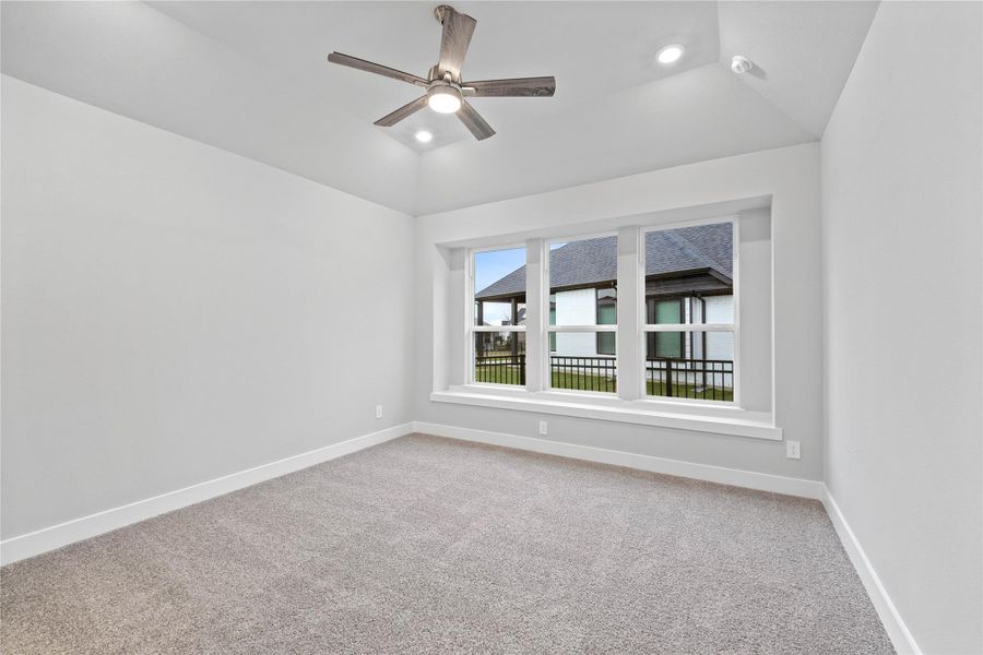 Relax and unwind after a long day in this impressive primary suite! This generously sized room offers plush carpet  flooring, neutral-toned paint, high sloped ceilings with a ceiling fan, and large windows for added comfort and tranquility.