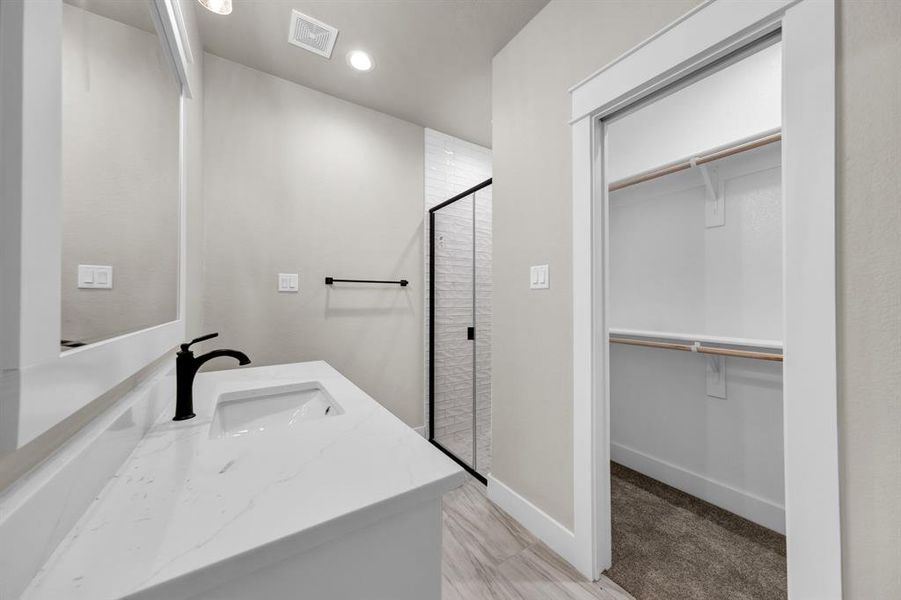 Bathroom featuring tile floors, a shower with shower door, and vanity