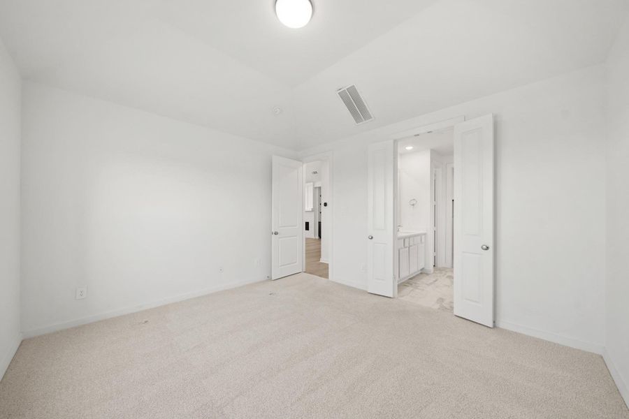 A cozy primary bedroom featuring elegant double doors that open to a beautifully designed bathroom retreat. A cozy primary bedroom featuring elegant double doors that open to a beautifully designed bathroom retreat.