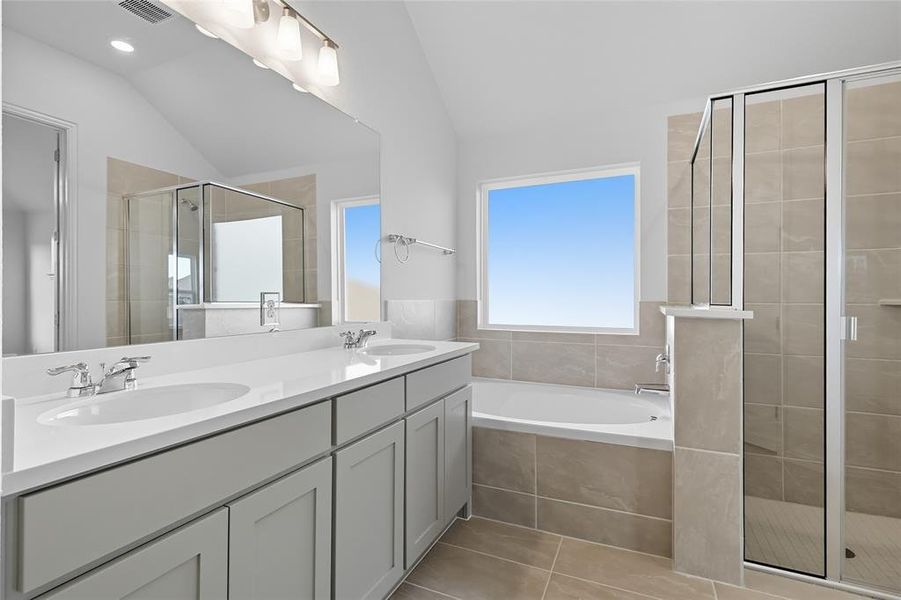 Bathroom featuring a shower stall, a bath, double vanity, vaulted ceiling, and light tile patterned floors Bathroom featuring a shower stall, a bath, double vanity, vaulted ceiling, and light tile patterned floors