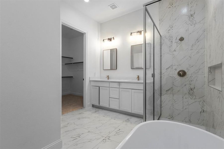 Full bath featuring marble look tile flooring, double vanity, a freestanding bath, and a marble finish shower Full bath featuring marble look tile flooring, double vanity, a freestanding bath, and a marble finish shower