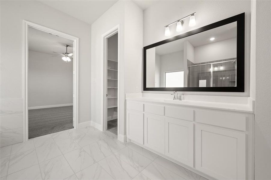 Bathroom with light marble finish flooring, a stall shower, vanity, a walk in closet, and ceiling fan