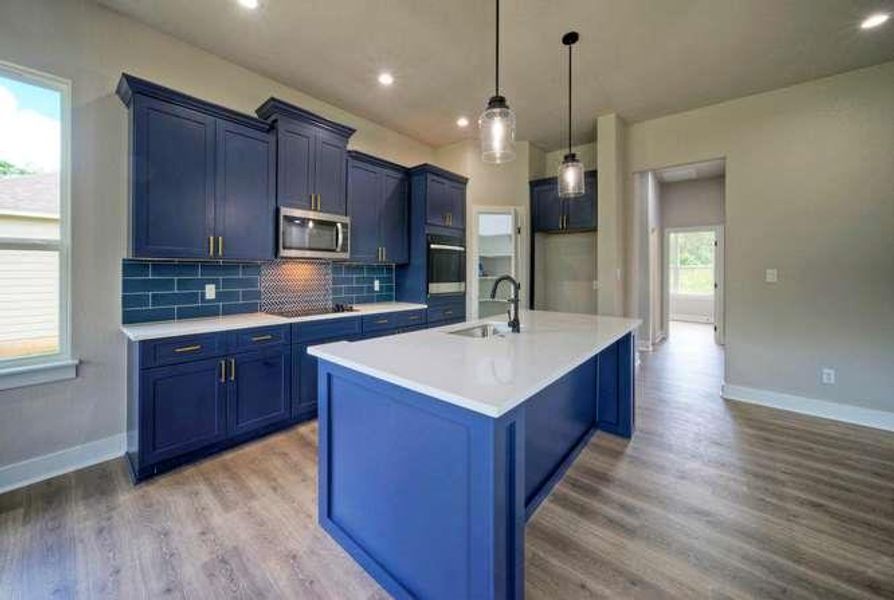 A vibrant kitchen boasts blue cabinetry and an expansive island, ready for culinary creations.