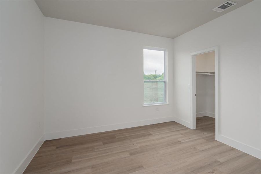 Unfurnished bedroom featuring light wood-type flooring, a walk in closet, and a closet