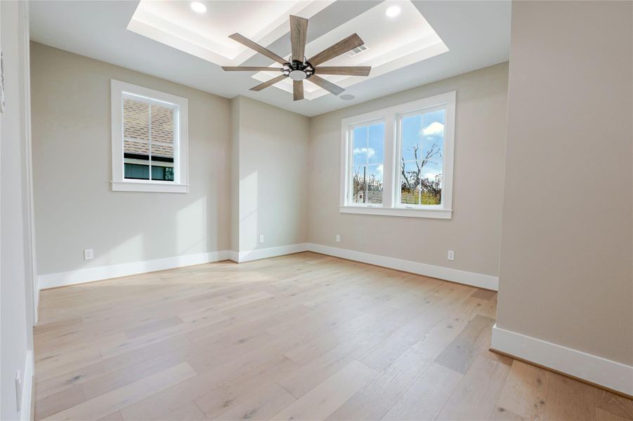 Spare room featuring light wood-style flooring, recessed lighting, a tray ceiling, and ceiling fan
