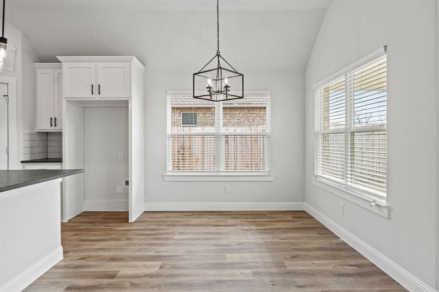 Unfurnished dining area featuring vaulted ceiling, light wood-type flooring, and a chandelier