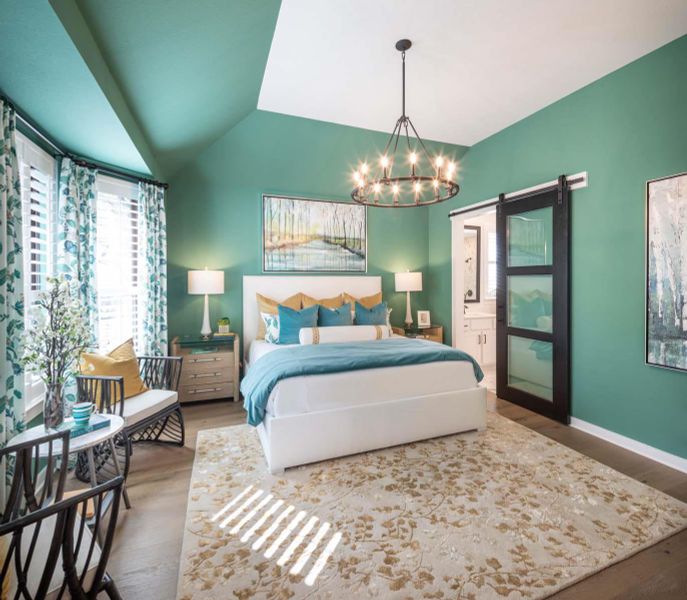 Bedroom with a barn door, lofted ceiling, an inviting chandelier, and wood finished floors