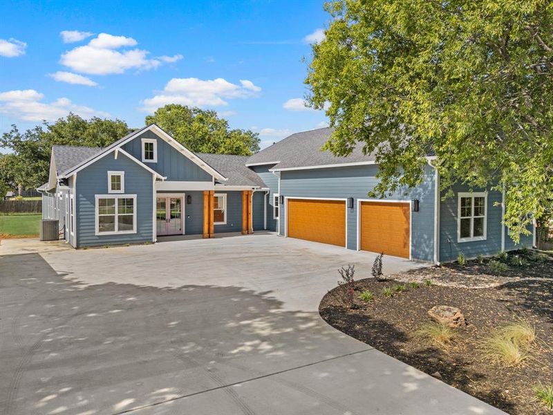 View of front of home featuring concrete driveway, an attached garage, a shingled roof, french doors, and board and batten siding View of front of home featuring concrete driveway, an attached garage, a shingled roof, french doors, and board and batten siding