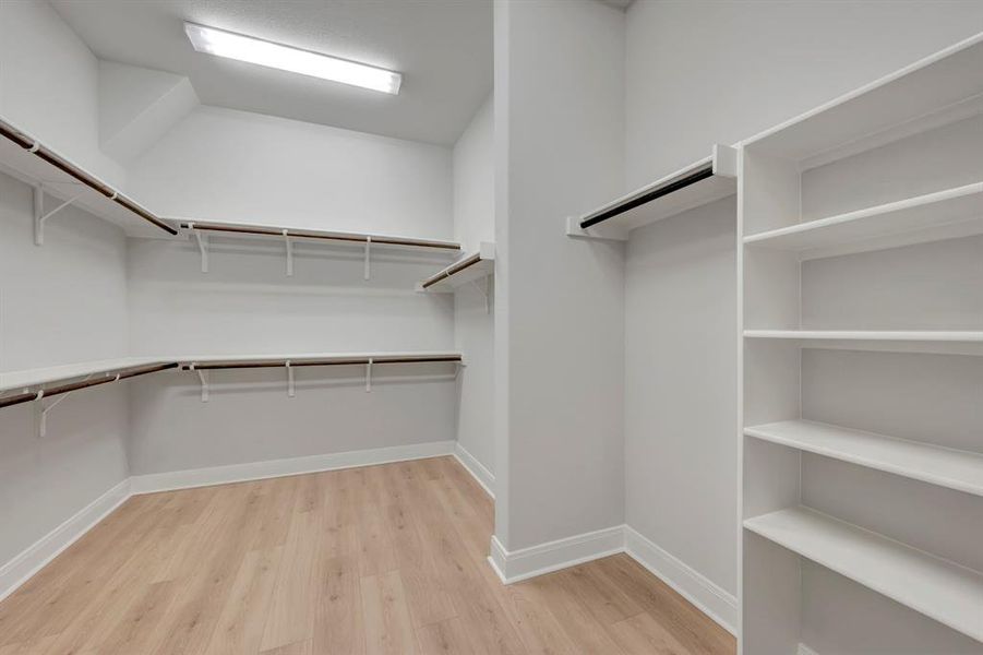 Walk in closet with light wood finished floors