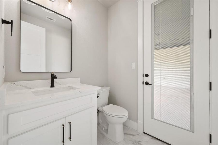 Bathroom featuring a white vanity with a rectangular sink, a black faucet, and a framed mirror