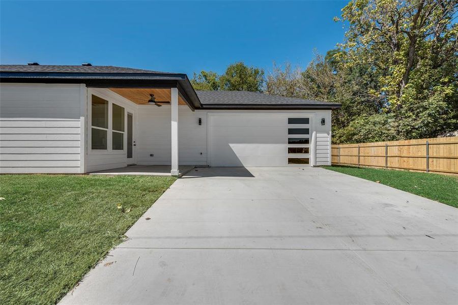 View of front of house with a front lawn, ceiling fan, and a garage