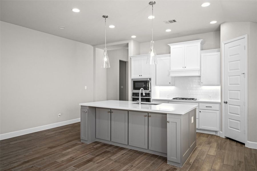 Island close-up showing the convenient Built-in Seating Space, prep sink, and modern pendant lighting.