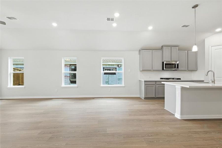 Kitchen with gray cabinets, recessed lighting, light wood finished floors, decorative light fixtures, and stainless steel microwave Kitchen with gray cabinets, recessed lighting, light wood finished floors, decorative light fixtures, and stainless steel microwave