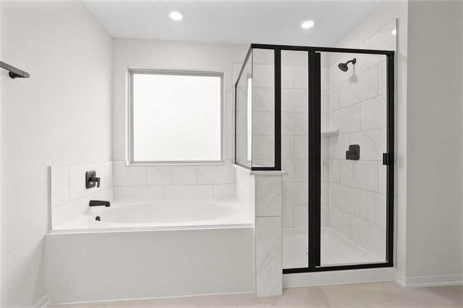 Additional view of the primary bathroom featuring a large garden tub, dark framed walk-in shower with tile surround, and tempered glass window for natural lighting.