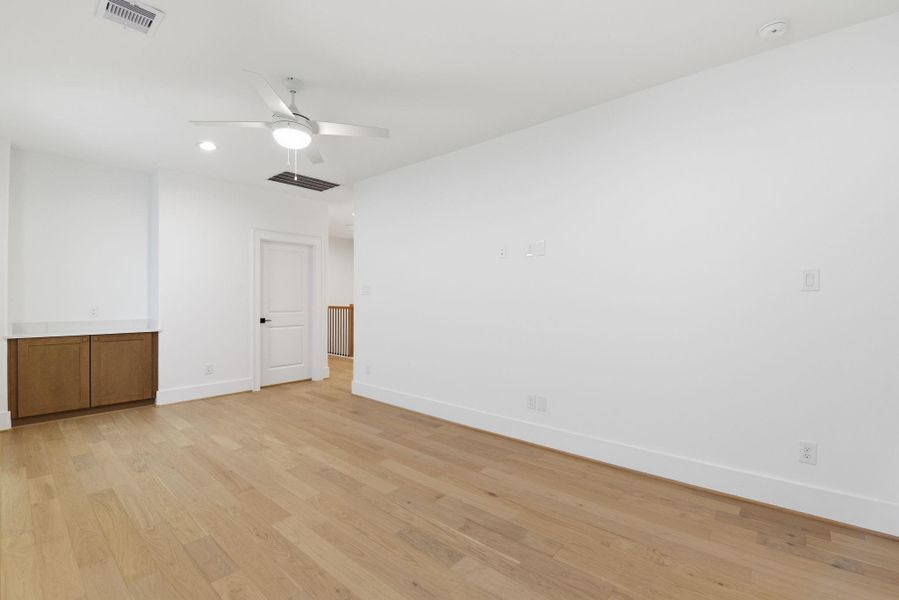 Bright and spacious upstairs flexroom featuring beautiful woodflooring, generous natural light,and convenient upstairs laundrywith ample storage. (Photo of a previous build, similar finishes.)